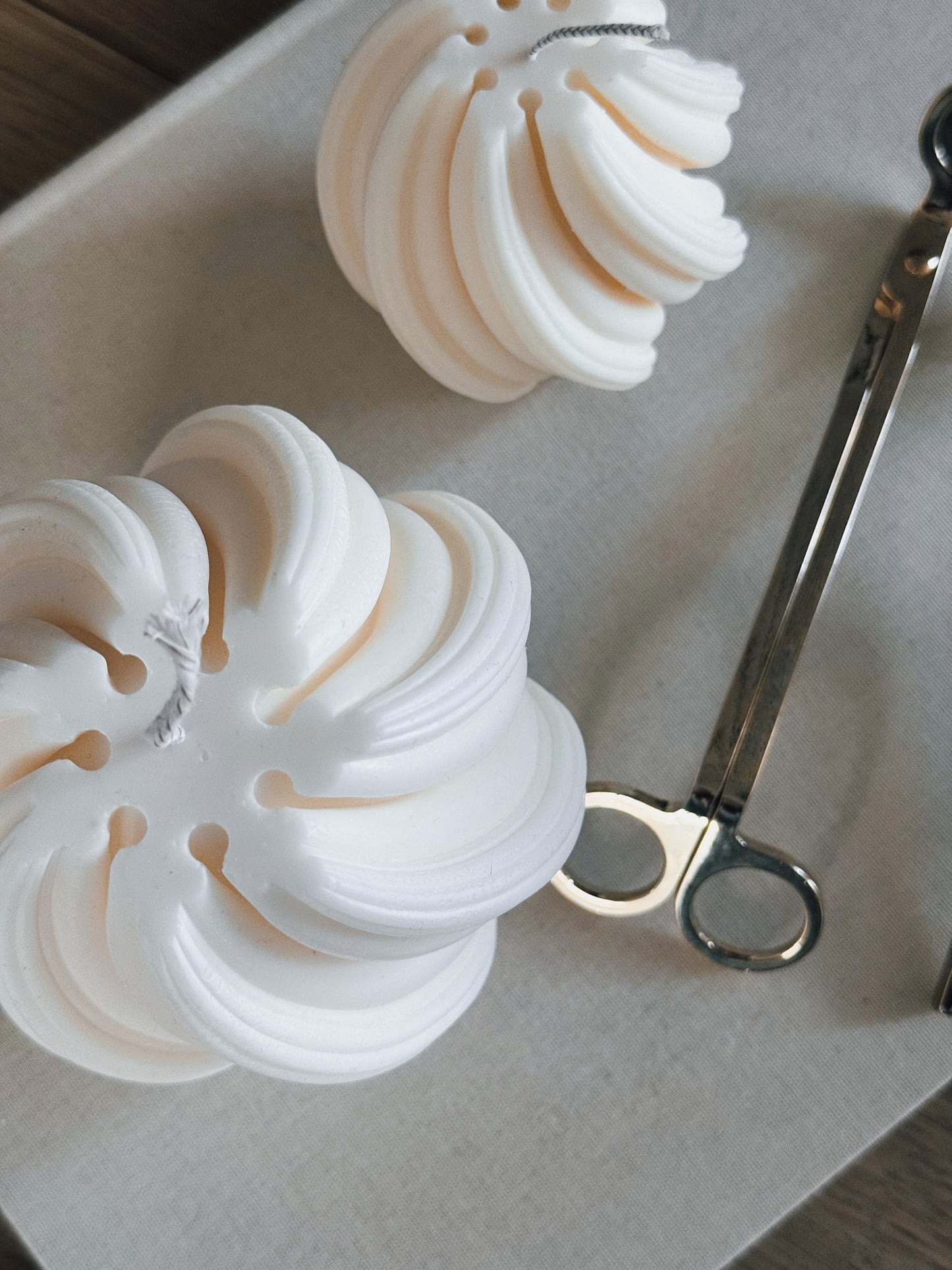 Makagi Swirl Kerzen aus Sojawachs in zwei Größen in weiß auf einem Buch stehend. Ansicht von oben