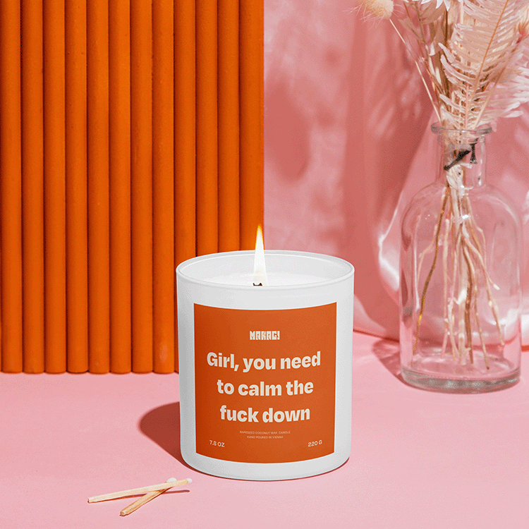 Makagi Duftkerze mit Girl you need to calm the fuck down stehend auf rosa Hintergrund mit Streichhölzern davor und Vase im Hintergrund
