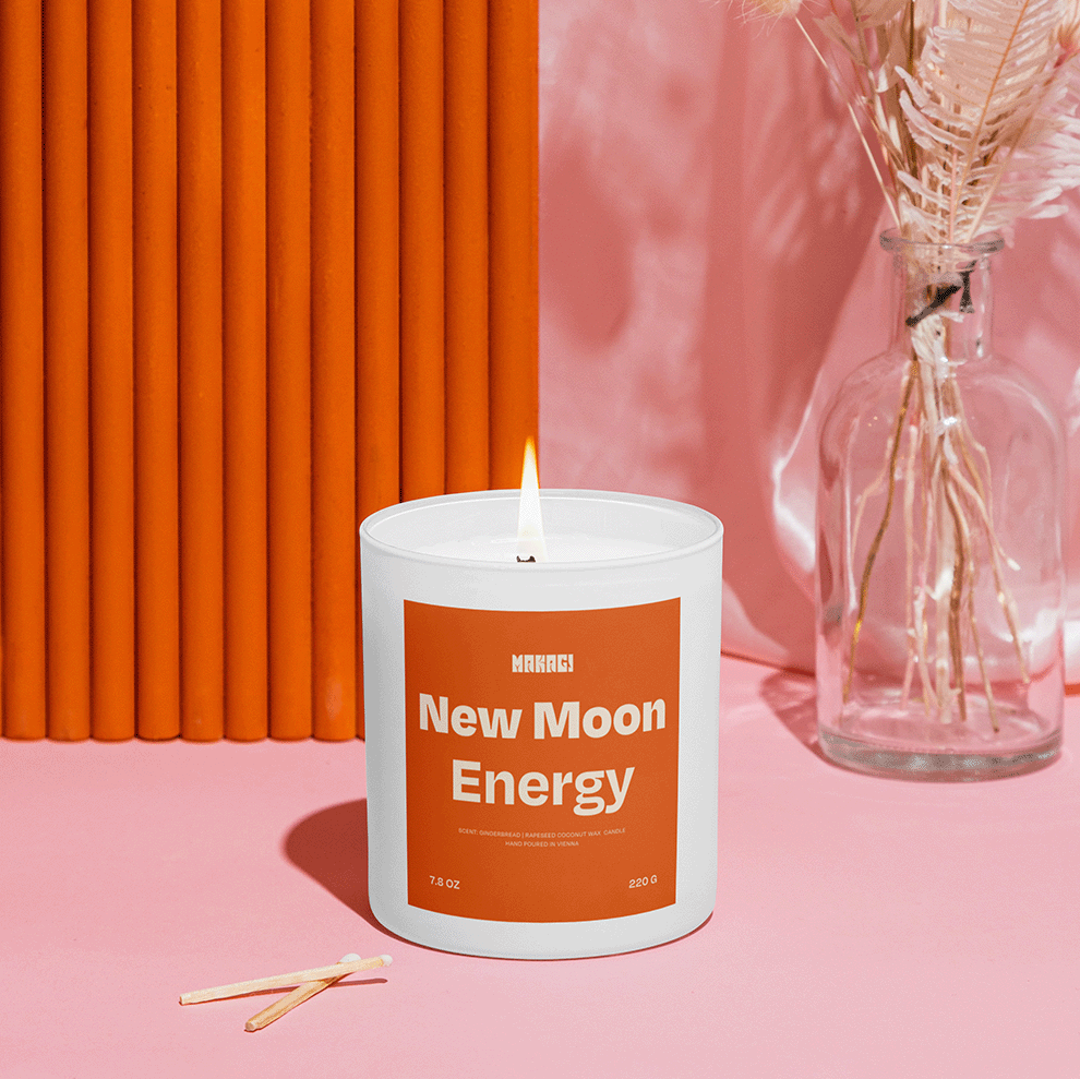 Makagi Duftkerze New Moon Energy stehend auf rosa Hintergrund mit Streichhölzern davor und vase im Hintergrund